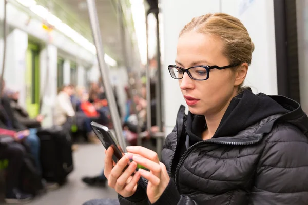 Chica joven leyendo desde la pantalla del teléfono móvil en metro . —  Fotos de Stock
