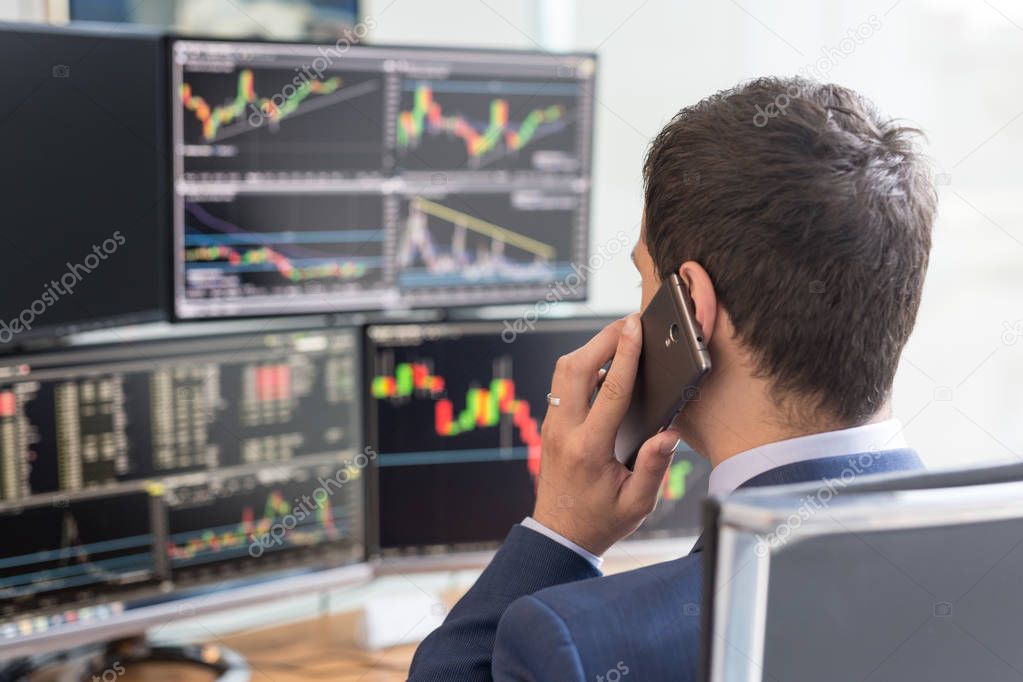 Over the shoulder view of computer screens and stock broker trading online.