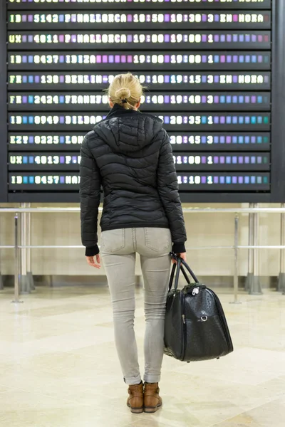 Feminino viajante verificando uma placa de partidas no terminal do aeroporto hall . — Fotografia de Stock