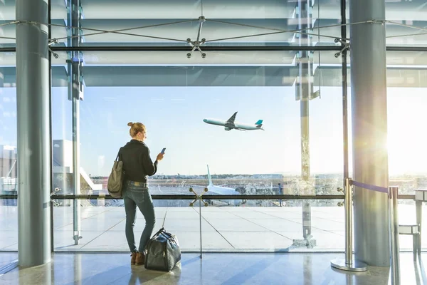 Jonge vrouw te wachten op de luchthaven, op zoek door het raam van de poort. — Stockfoto