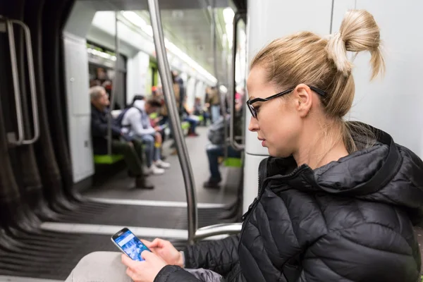 지하철에서 휴대 전화 화면에서 읽고 있는 소녀. — 스톡 사진