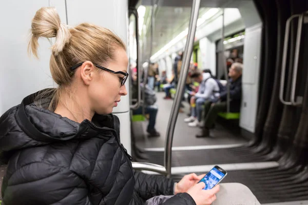 Metrodaki cep telefonu ekranından okuyan genç bir kız.. — Stok fotoğraf