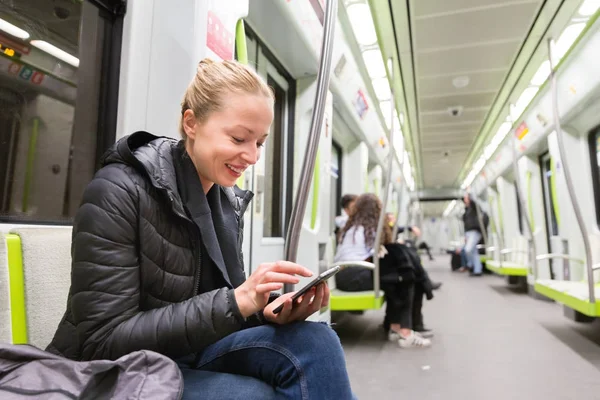 Νεαρό κορίτσι ανάγνωση από την οθόνη του κινητού τηλεφώνου στο μετρό. — Φωτογραφία Αρχείου