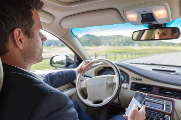 Homme d'affaires utilisant un téléphone portable et textos tout en conduisant ne faisant pas attention à la route . — Photo