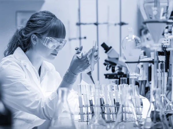 Joven científico pipeteando en laboratorio de ciencias de la vida. — Foto de Stock