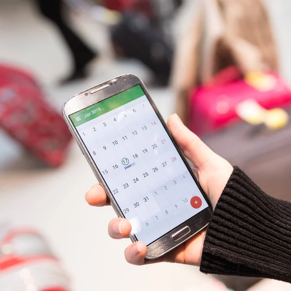 Γυναίκα έλεγχος ημερολογίου πληροφορίες στο κινητό τηλέφωνο που κάθεται στο τερματικό σταθμό του αεροδρομίου. — Φωτογραφία Αρχείου