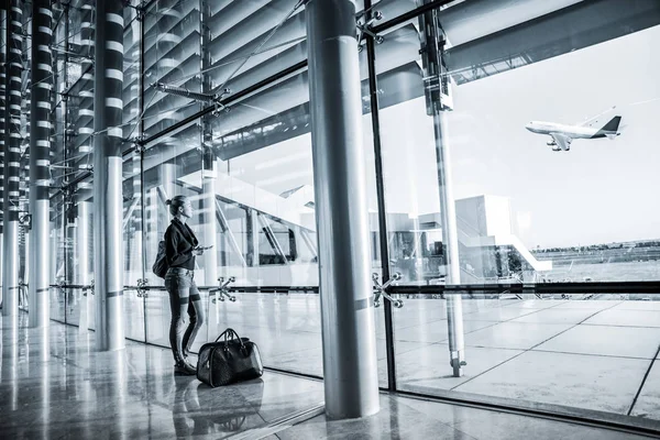 Giovane donna in attesa in aeroporto, guardando attraverso la finestra del cancello . — Foto Stock