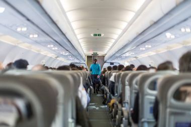 Uçuş sırasında koltuklarda servis yapan hostesli ticari uçağın içi..