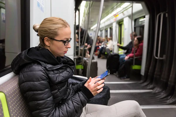 Metrodaki cep telefonu ekranından okuyan genç bir kız.. — Stok fotoğraf