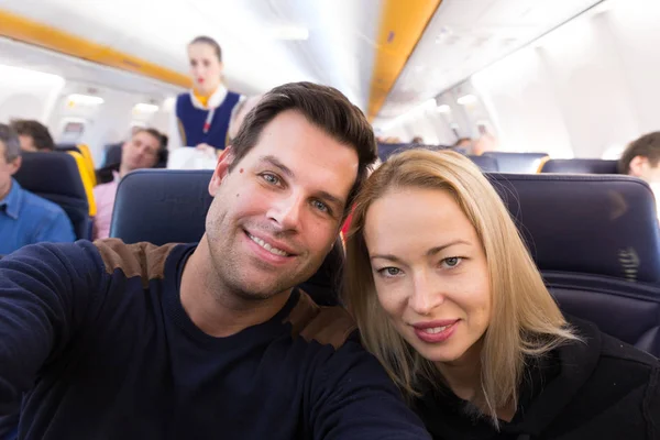 Молодая красивая пара делает селфи на коммерческом самолете . — стоковое фото