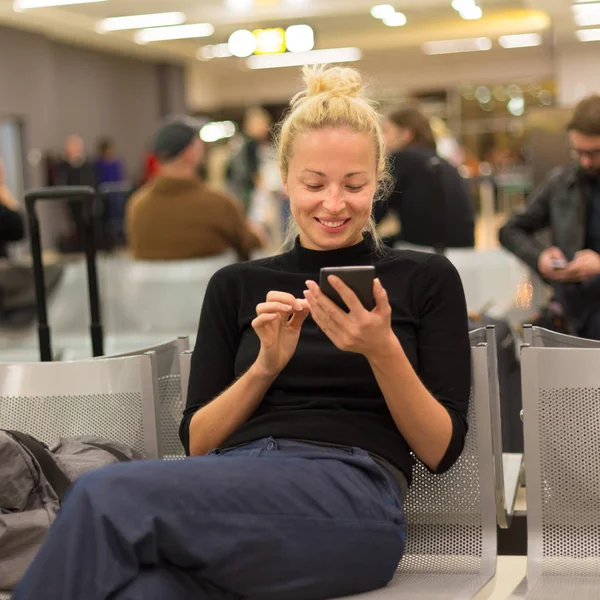 Señora usando el teléfono inteligente mientras espera en las puertas de salida del aeropuerto . —  Fotos de Stock