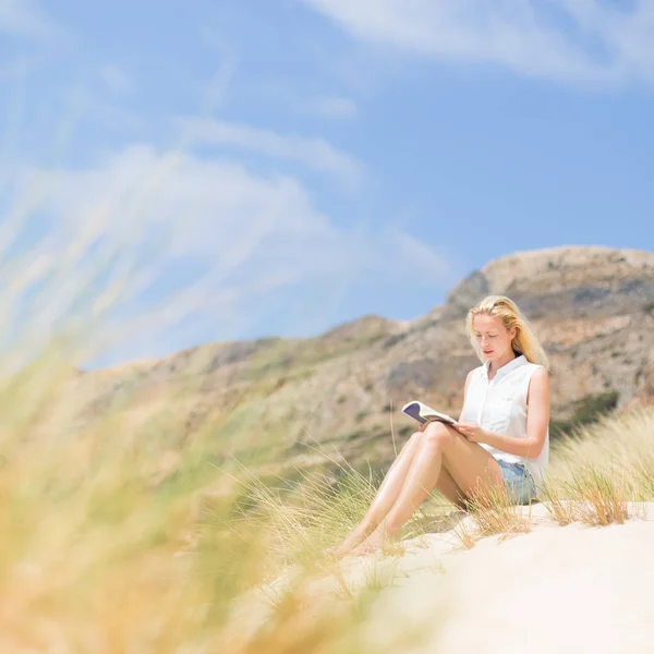 Frau liest Buch, genießt Sonne am Strand. — Stockfoto