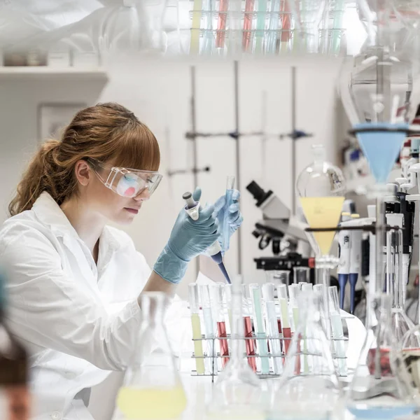 Joven científico pipeteando en laboratorio de ciencias de la vida. — Foto de Stock