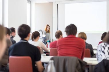 Üniversitedeki konferans salonunda sunum yapan kadın..