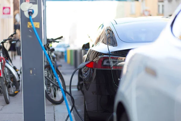 Carregando carro elétrico moderno na rua como futuro da indústria automotiva . — Fotografia de Stock