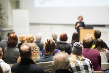 Üniversitedeki konferans salonunda sunum yapan kadın..