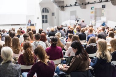 Üniversitedeki konferans salonunda sunum yapan kadın..