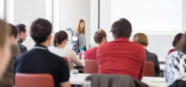 Üniversitedeki konferans salonunda sunum yapan kadın..
