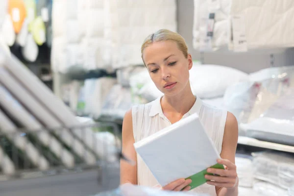 Woman buying bed sheets for her bed in modern home furnishings store. — Stock Photo, Image