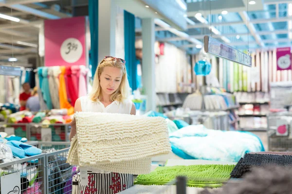 Mujer eligiendo una alfombra en la tienda de muebles para el hogar moderno . — Foto de Stock