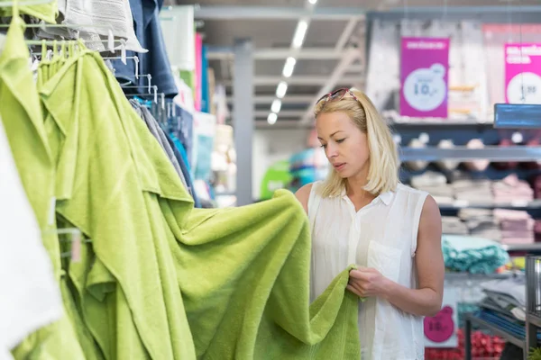 Mujer bonita y joven eligiendo la toalla en la tienda de muebles para el hogar moderno . — Foto de Stock