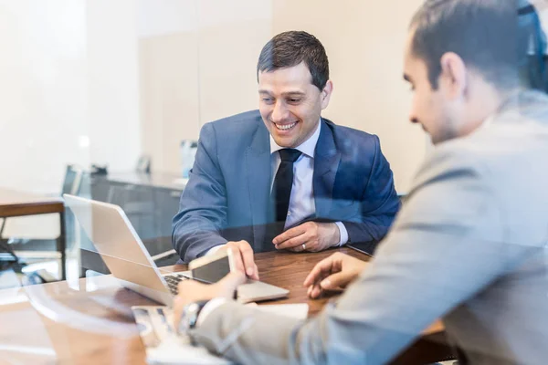 Dos jóvenes hombres de negocios que utilizan ordenador portátil en la reunión de negocios . — Foto de Stock