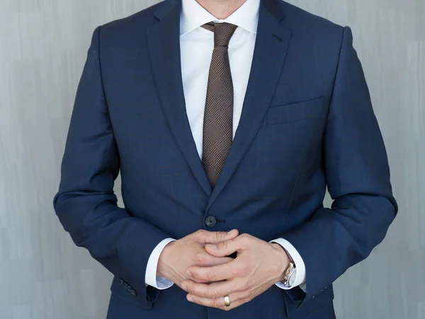 Torso di un uomo d'affari in piedi con le mani serrate in posizione centrale in un classico abito blu navy . — Foto Stock