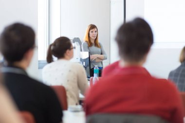Üniversitedeki konferans salonunda sunum yapan kadın..