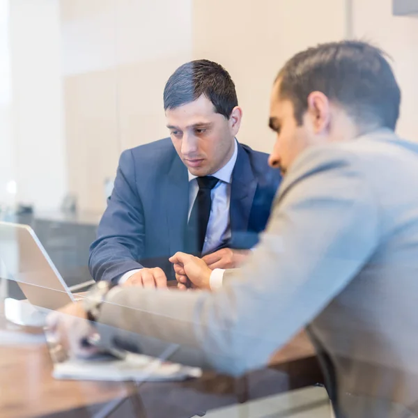 Två unga affärsmän använder bärbar dator på affärsmöte. — Stockfoto