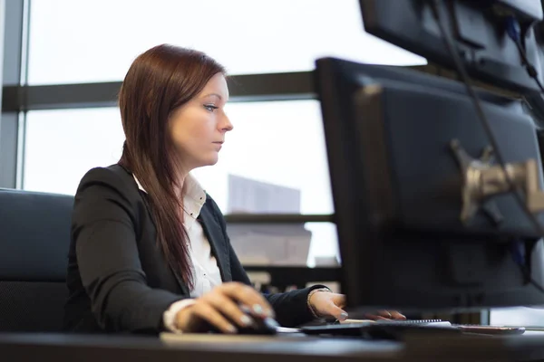Na co dzień bizneswoman, praca w biurze, siedząc przy biurku, wpisując na klawiaturze, patrząc na ekranie komputera. — Zdjęcie stockowe