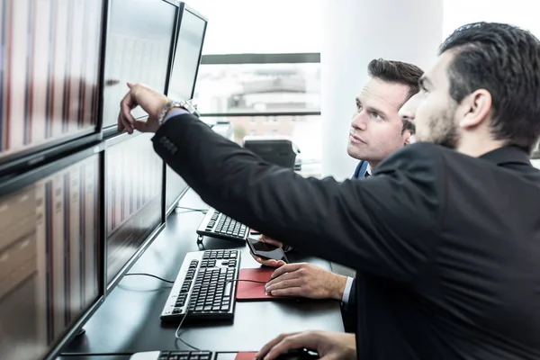 Operadores de bolsa mirando los datos del mercado en las pantallas de ordenador. — Foto de Stock