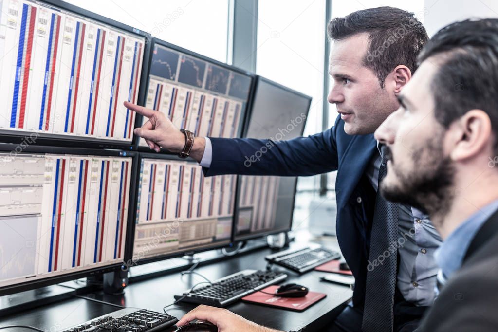 Stock traders looking at market data on computer screens.