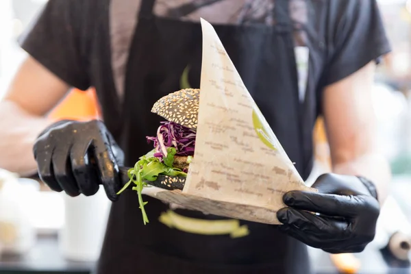 Chef que serve hambúrguer de peixe vegetariano orgânico no festival internacional de comida urbana de rua . — Fotografia de Stock