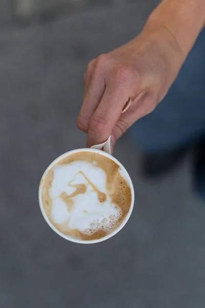 Mão segurando uma xícara de café para ir . — Fotografia de Stock
