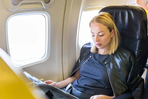 飛行中に飛行機の中で雑誌を読む女性. — ストック写真