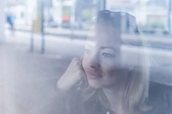 Young woman traveling by train, looking out window while sitting in train. — Stock Photo, Image