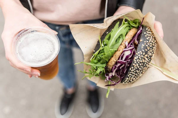 Жіночі руки тримають смачний органічний лосось Вегетаріанський бургер та домашнє пиво МФА . — стокове фото