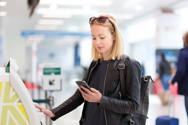 Mujer caucásica casual usando aplicación de teléfono inteligente y máquina de check-in en el aeropuerto conseguir la tarjeta de embarque . —  Fotos de Stock