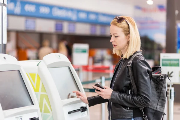 Dorywczo kaukaski kobieta przy użyciu aplikacji smart telefonu i automatu na lotnisku coraz kartę pokładową. — Zdjęcie stockowe