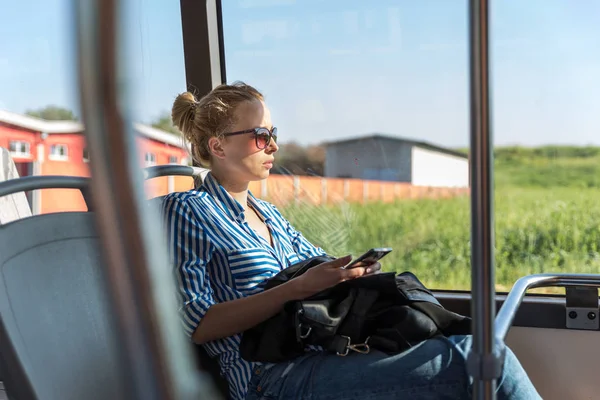 Retrato de mulher dirigindo em ônibus em movimento sentado pela janela usando telefone celular . — Fotografia de Stock