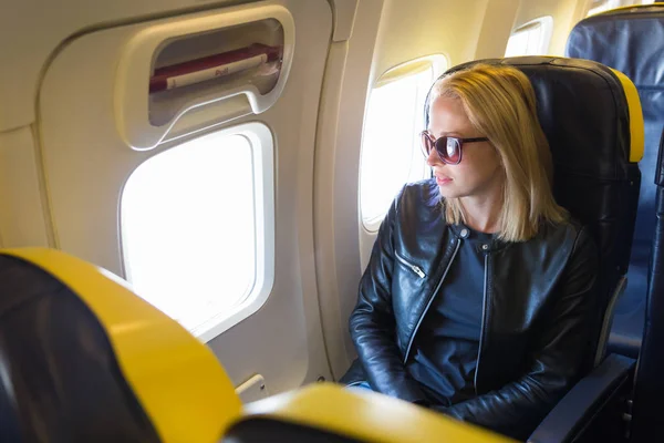 Женщина смотрит в окно самолета во время полета . — стоковое фото