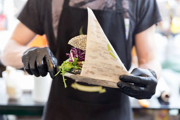 Chef sirviendo hamburguesa vegetariana orgánica de pescado en el festival internacional de comida urbana callejera . —  Fotos de Stock