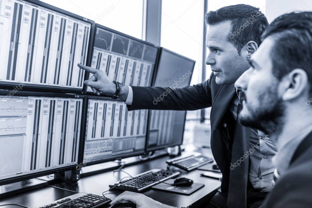 Stock traders looking at market data on computer screens.