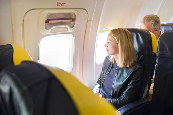 Woman looking through the window on airplane during flight. — Stock Photo, Image