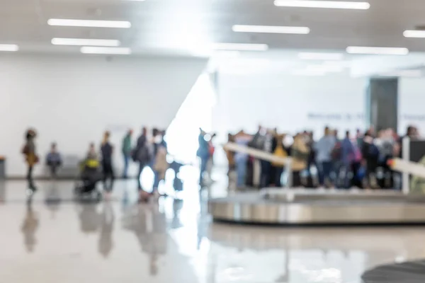 Emberek várnak a repülőtér érkezési csarnokában csomagjaikat blured képe. — Stock Fotó