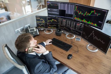 Borsa simsarının internet üzerinden yaptığı görüşün üzerinden, cep telefonuyla konuşuyor..