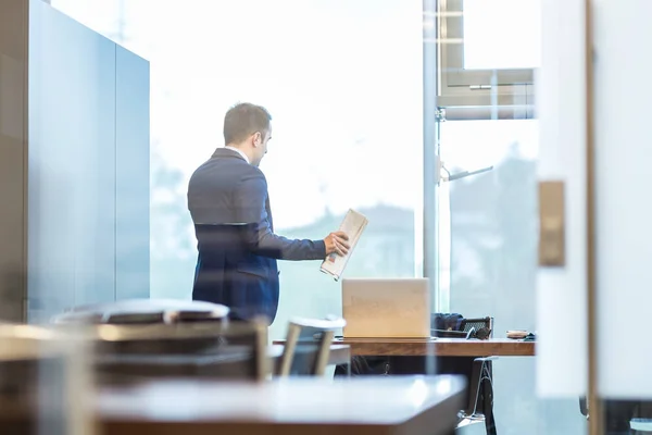 Zakenman praat op een mobiele telefoon terwijl hij door het raam kijkt. — Stockfoto