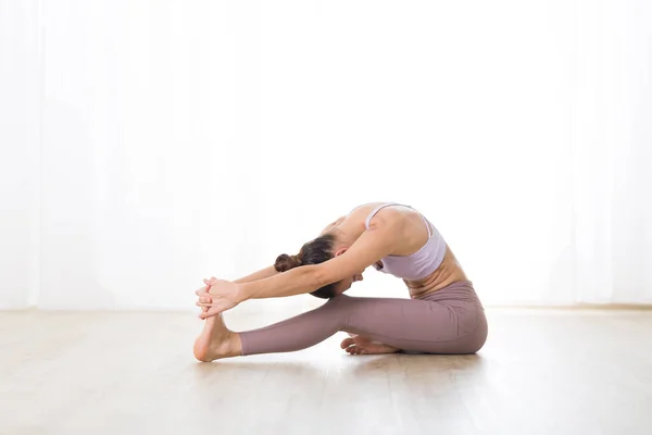 Retrato de una hermosa joven deportista activa practicando yoga en estudio. Hermosa chica practica Janushiransa con Paschimotthanasana, cabeza a rodilla con pose de yoga —  Fotos de Stock