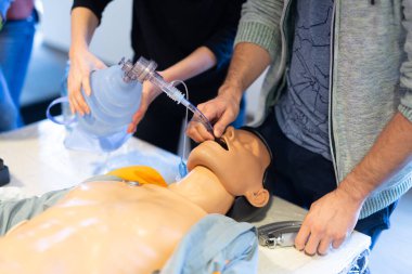 Tıp doktoru uzmanı, tıp eğitimi ve atölyesinde hasta entübasyon yöntemi gösteriyor. Katılımcılar yeni tıbbi prosedürler ve teknikler öğreniyorlar.