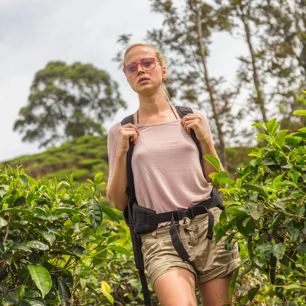 Active caucasian blonde woman enjoing fresh air and pristine nature while tracking among tea plantaitons near Ella, Sri Lanka. Bacpecking outdoors tourist adventure — Stock Photo, Image